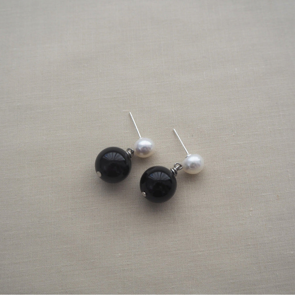 Photo of a pair of stud earrings with a small freshwater pearl with a drop attachment which has a larger black agate round stone attached.