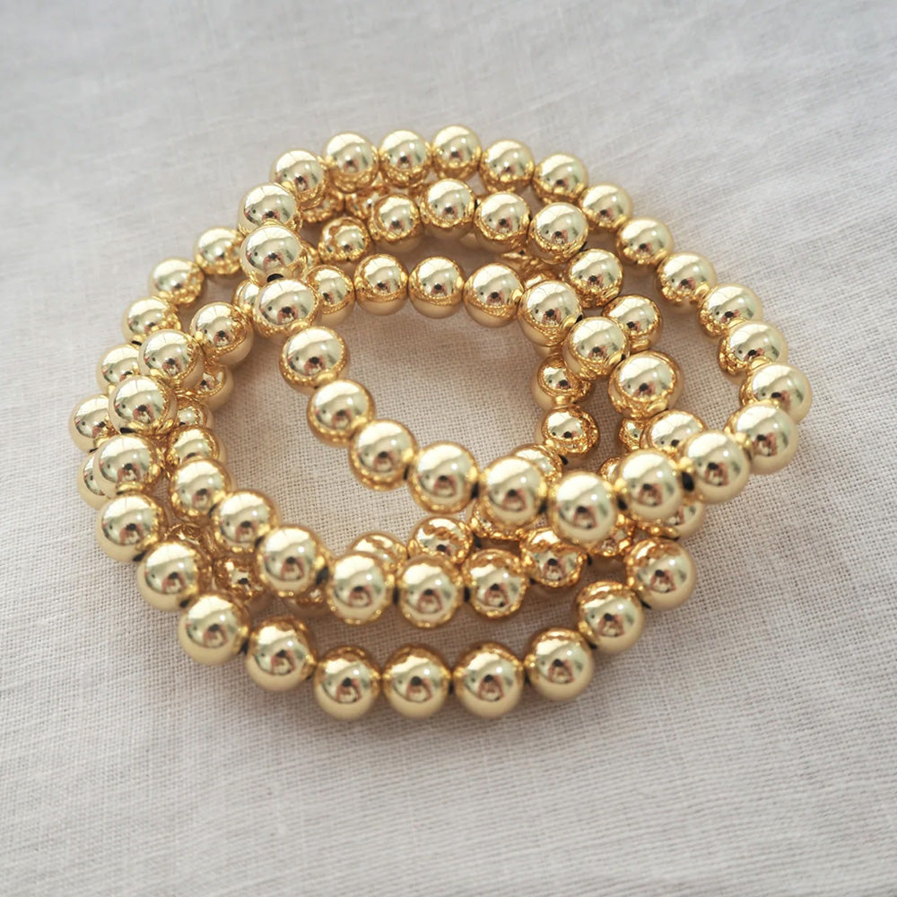 Photo of a stack of three gold ball chain bracelets.