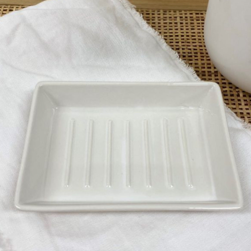 White rectangular ceramic soap dish with raised line detail on inside of dish