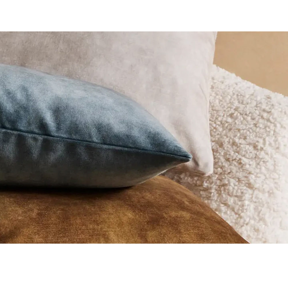Photo of aqua blue velvet cushion mixed with other velvet coloured cushions on a sofa