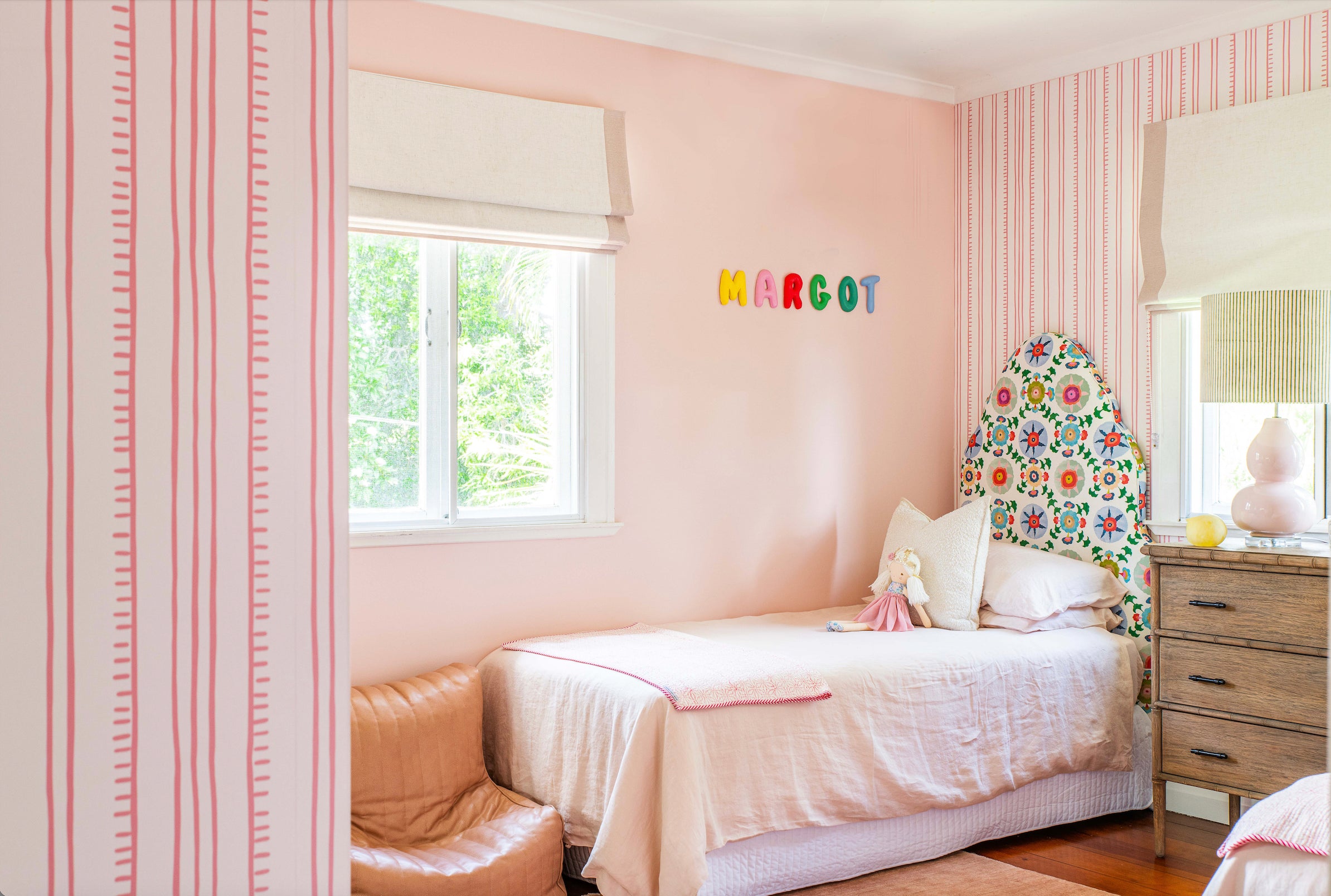 Bedroom with pink walls, floral headboard, and colorful letters 