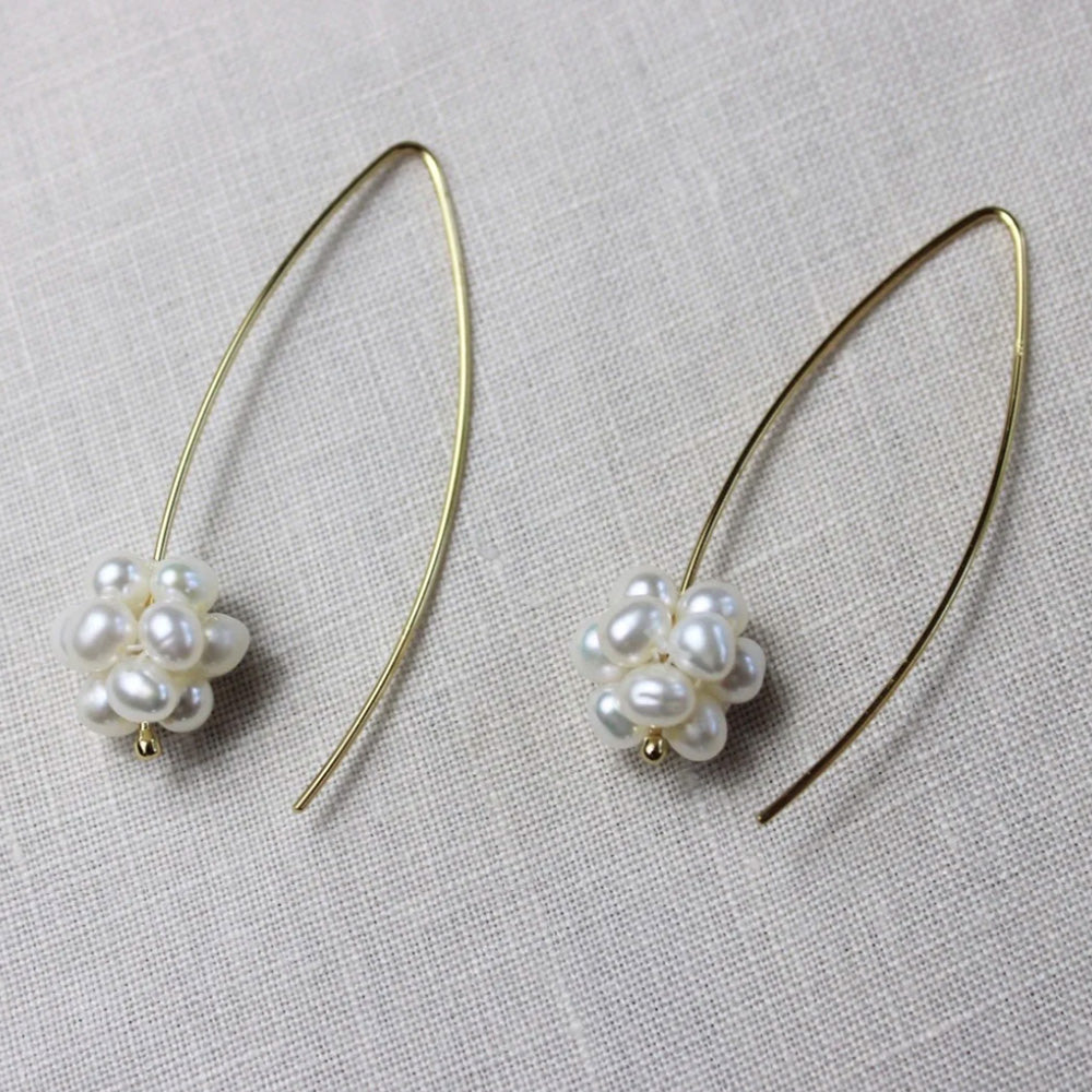 Photo of a pair of gold long hoop earrings with a cluster of small freshwater pearls at one end.
