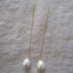 Photo of a gold chain earring thread with a freshwater pearl at the end. 