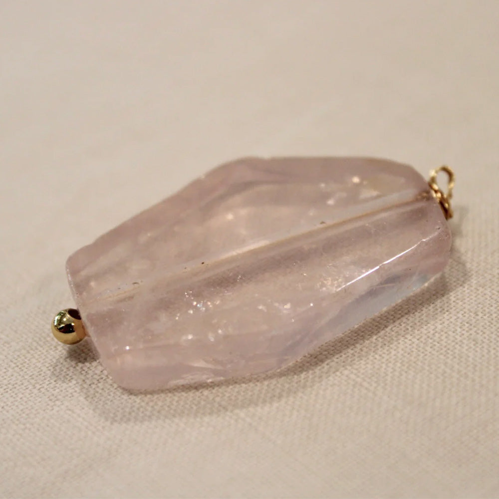 Close up photo of a pink rose quartz crystal pendant