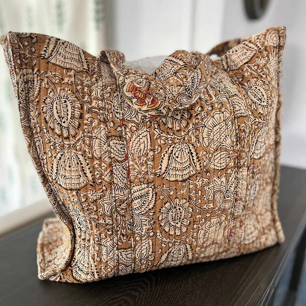 Close up photo of coffee spice floral quilted block printed tote bag sitting on a dark benchtop.