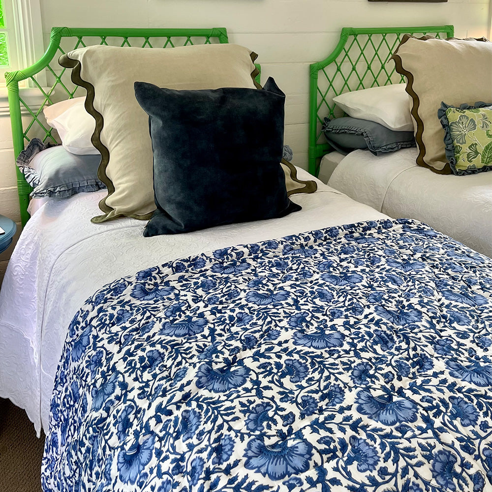 Photo of a blue and white floral quilted bedspread folded over the end of a bed.