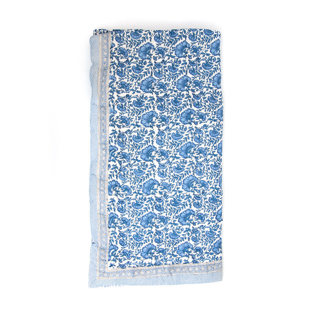 Photo of a blue and white floral quilted bedspread folded.
