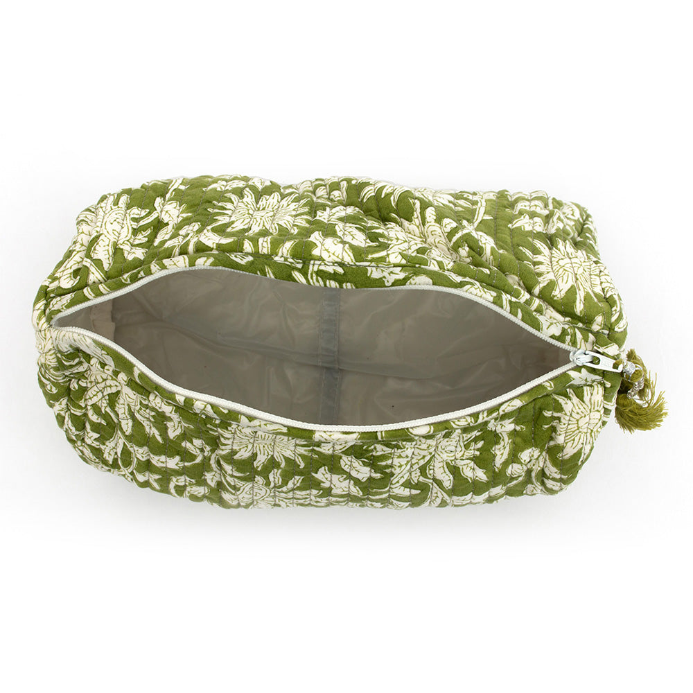 Close up photo of a forest green and white floral block printed quilted cosmetic pouch from an aerial viewpoint showing the pouch zipped open so you can see the inside white plastic waterproof lining.