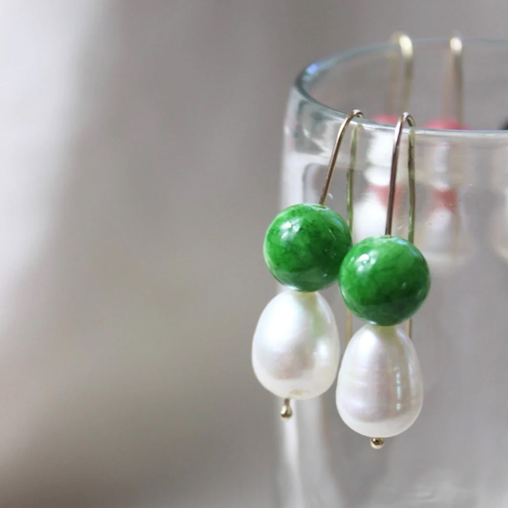 Photo of gold hook earrings with a large teardrop shaped freshwater pearl and a round emerald green coloured agate stone.