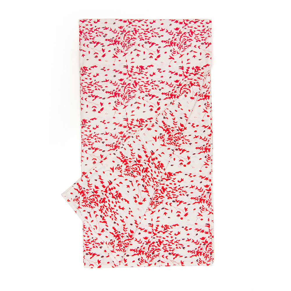 Photo of a folded white, red and deep burgundy red floral cotton tablecloth with one corner turned upwards.