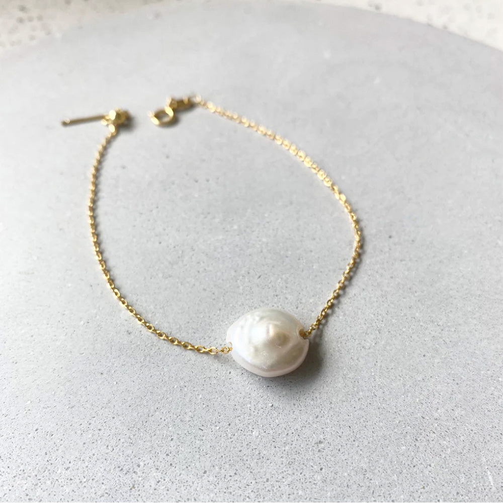 Photo of a fine gold chain bracelet with a feature freshwater pearl.