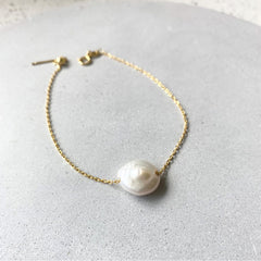 Photo of a fine gold chain bracelet with a feature freshwater pearl.