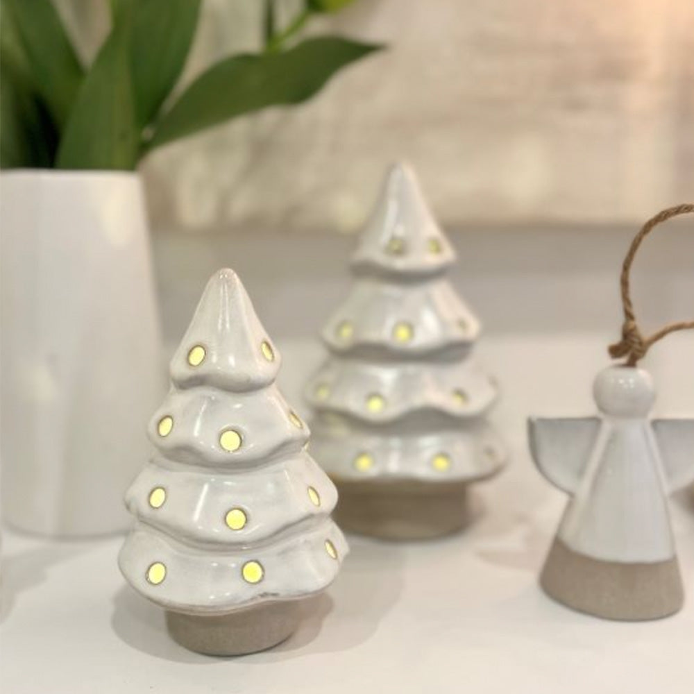 Close up photo of cream ceramic Christmas tree with holes to show light coming through the holes