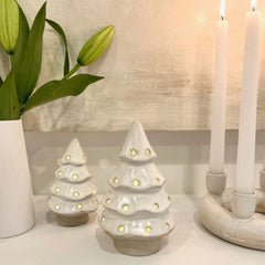 Close up photo of cream ceramic Christmas tree with holes to show light coming through the holes