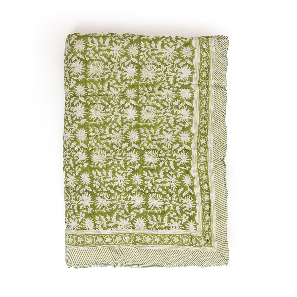 Photo of a forest green and white floral quilted bedspread folded.