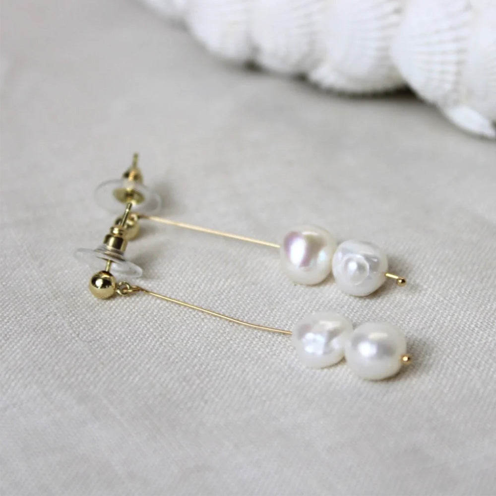 Photo of a gold bar stud earring with two small freshwater pearls at the end of the bar.