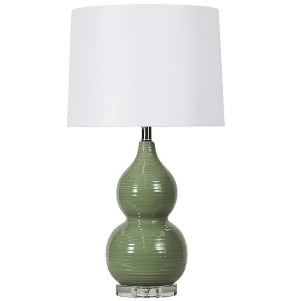 Photo of sage green ceramic lamp with glass disc base and a plain white drum shade.
