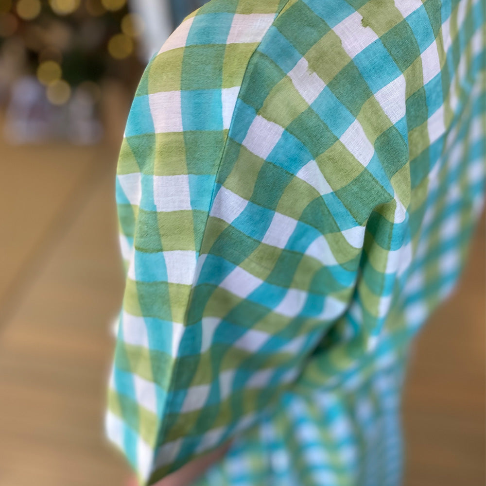Close up photo of lady wearing white, aqua blue and mint green check kaftan dress showing the shoulder and arm view of the dress.