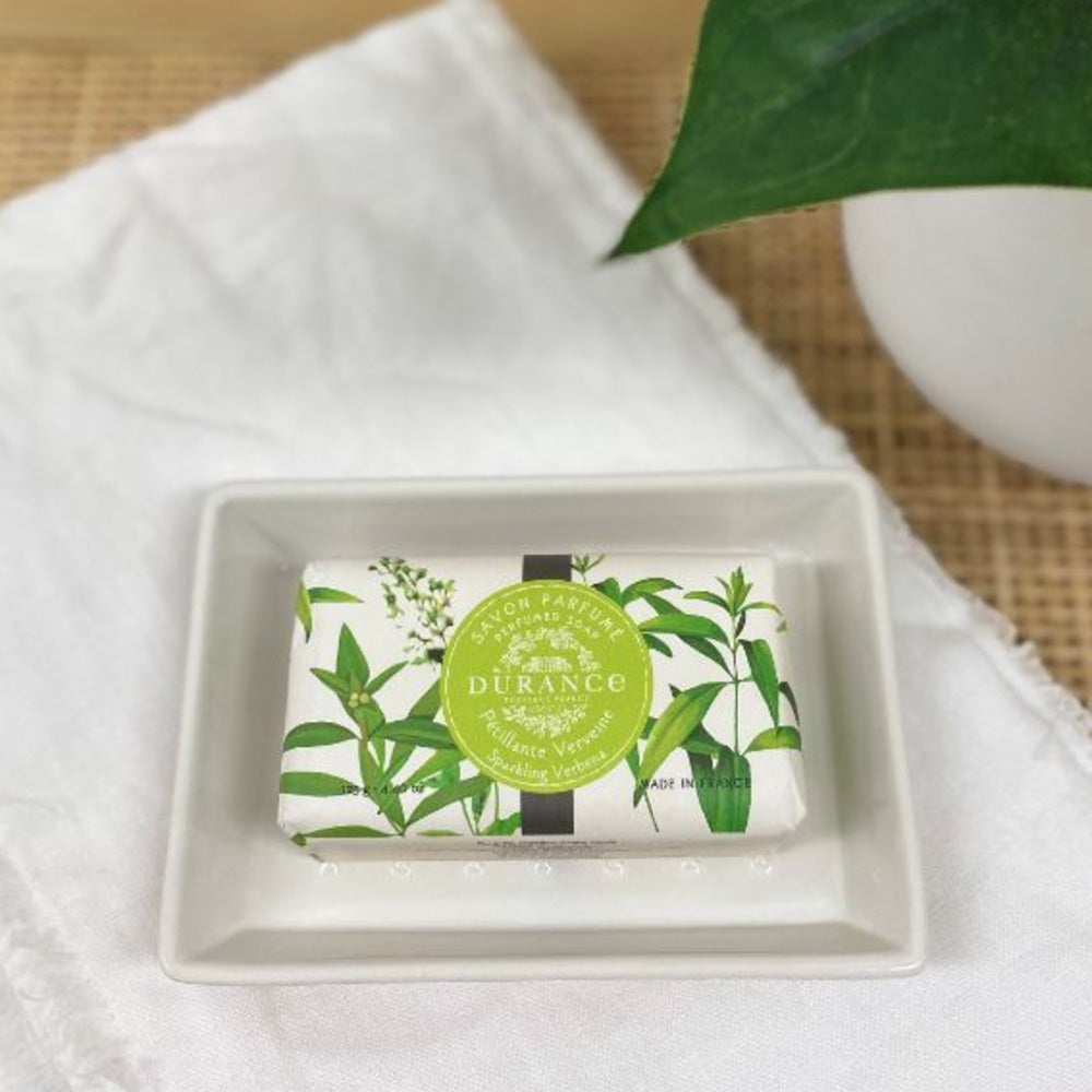 White ceramic rectangular soap dish with green and white wrapped soap bar sitting inside