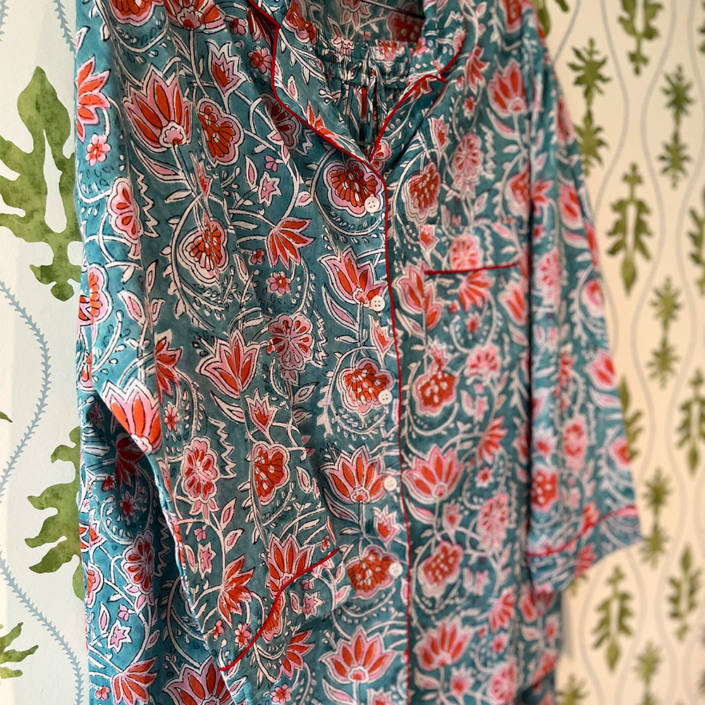 Photo of Augusta coral flower on aqua background cotton pyjamas hanging in front of green floral wallpaper