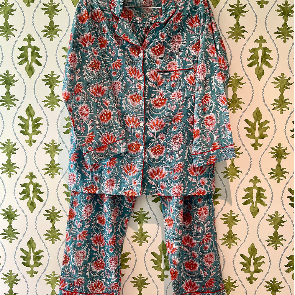 Photo of Augusta coral flower on aqua background cotton pyjamas hanging in front of green floral wallpaper