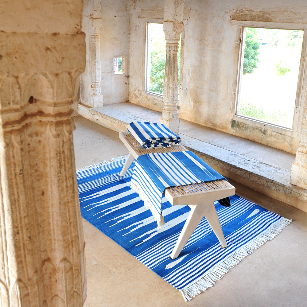 Photo of blue and white Arizona cotton dhurrie rugs on floor and folded on bench seat