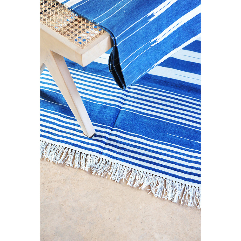 Photo of blue and white Arizona cotton dhurrie rugs on floor and folded on bench seat