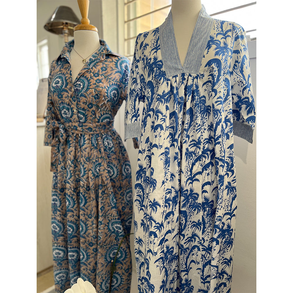 Photo showing fabric detail and pattern on Adaline Dress in beige and French blue hanging on manequin beside Collette dress in Blue Palm